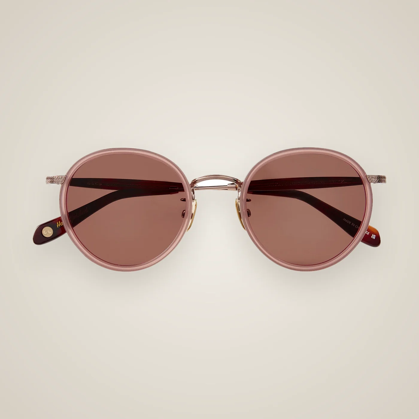 Lunettes de soleil Garrett Leight repliées, monture ronde rose avec pont en métal doré